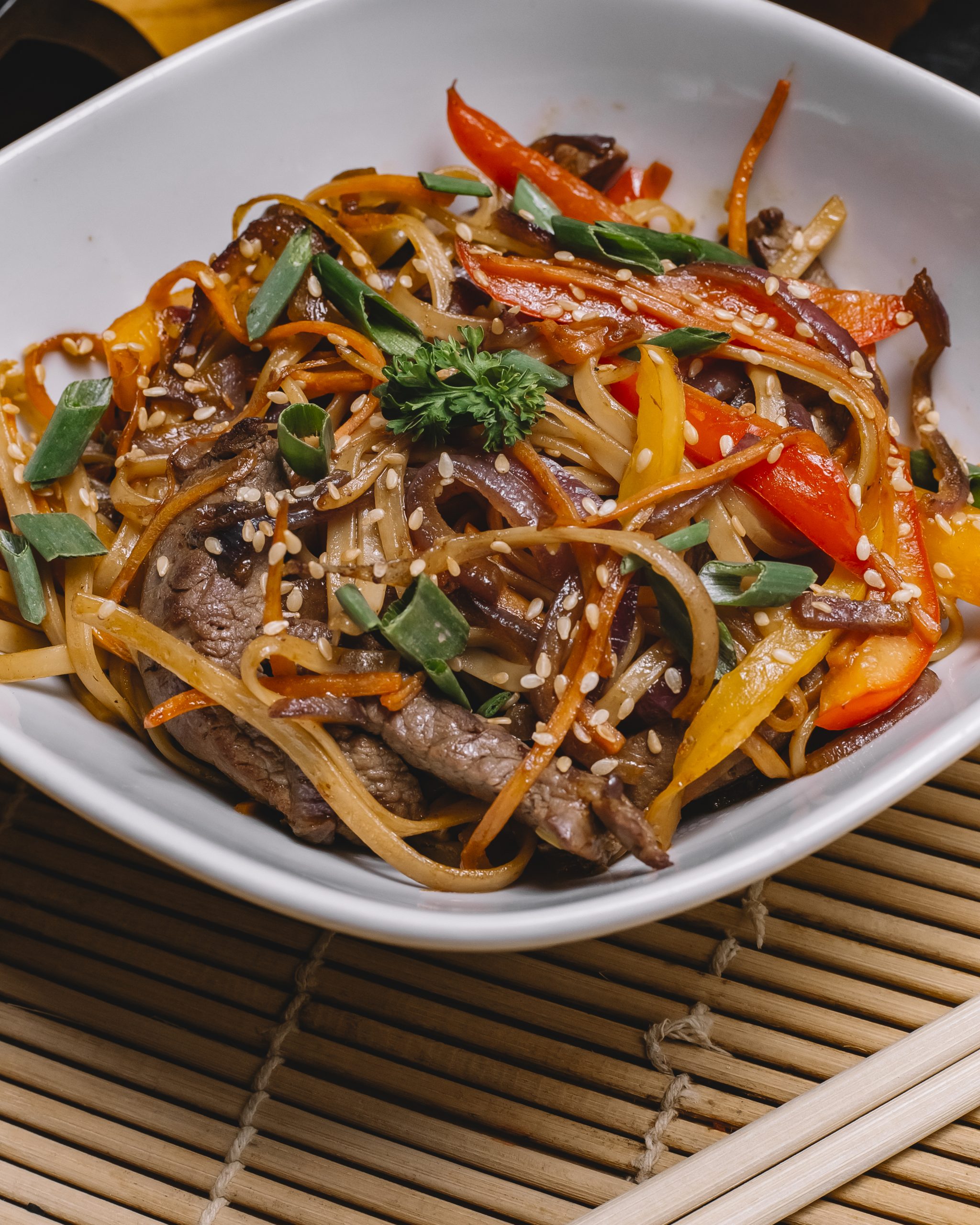 Side View Stir Fried Noodles With Grilled Meat Bell Peppers Spring Onion Sesame Seeds